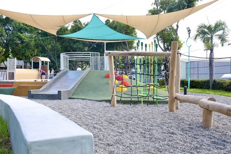 佳里體育公園特色遊戲場，遮陽帆布下有溜滑梯草坡、彩色攀爬點、繩網與原木平衡木，地面鋪碎石。