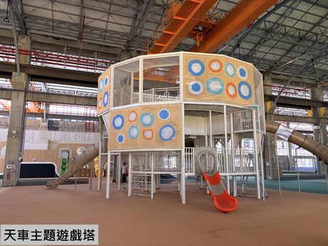 高雄親子遊樂園區內以廢棄鋼鐵廠房改建的「天車主題遊戲塔」，八角形攀爬塔搭配黃色與紅色滑梯，上方保留原廠房天車軌道。