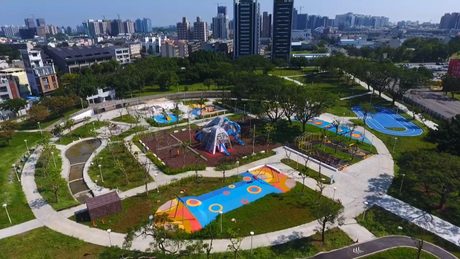 楠梓區藍田公園空拍全景，園內可見帳篷造型鹽山主塔、彩色地墊遊戲場與環狀步道。