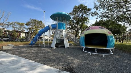 同盟公園的水母主題遊戲場，藍白色燈塔造型攀爬塔與粉藍色水母造型攀爬殼，樹蔭環繞。