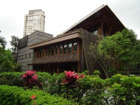 臺北市立圖書館北投分館的木造建築外觀，被綠樹與灌木環繞。
