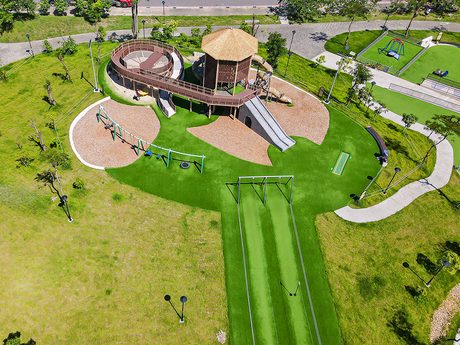 空拍十四張歷史公園的遊戲場，有茅草屋頂的木造遊戲塔、長溜滑梯、鞦韆和草坪上的滑索。