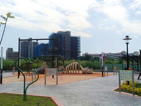 逗逗龍公園的恐龍主題遊戲區，有三角龍骨架造型的地景遊具、繩網攀爬架和解說牌。