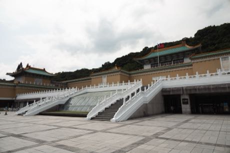 國立故宮博物院北部院區主館外觀，白色石階通往黃牆綠瓦的建築，背後是山坡。