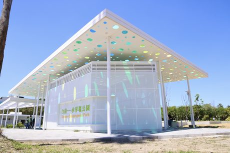 水萍塭公園新建的白色大屋頂入口建築，屋簷有彩色圓孔，牆上寫著「台南---水萍塭公園」。