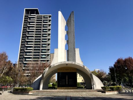 八二三紀念公園的臺海戰役紀念碑，白色拱形基座上立著兩片高聳的碑翼，晴天藍天背景。