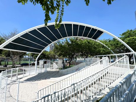 廍興公園的大碗公磨石子溜滑梯，上方有白色弧形遮陽棚與階梯步道。