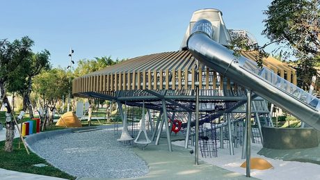 中央公園飛行美樂地遊戲場的主題滑梯與繩網攀爬設施，晴天下方為碎石與地墊鋪面。