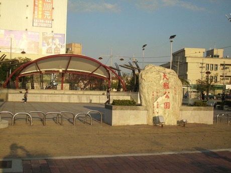 大雅公園入口廣場，中央是刻有「大雅公園」的名稱石，後方有紅色弧形棚架
