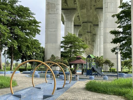 大甲溪畔生態公園位於國道三號高架橋下，前方有弧形鋼管攀爬設施，遠處是涼亭與遊具。