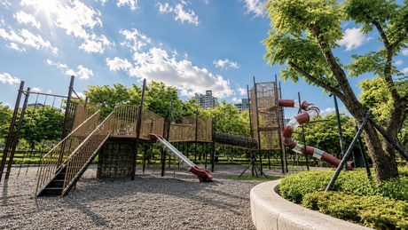青山河濱公園的鰻魚主題大型組合遊具，有攀爬網、爬梯和紅白條紋的管狀溜滑梯，地面鋪碎石。