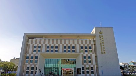 桃園防災教育館大樓正面，米白色建築外牆上有「桃園市政府消防局訓練中心暨防災教育館」字樣，晴朗藍天。